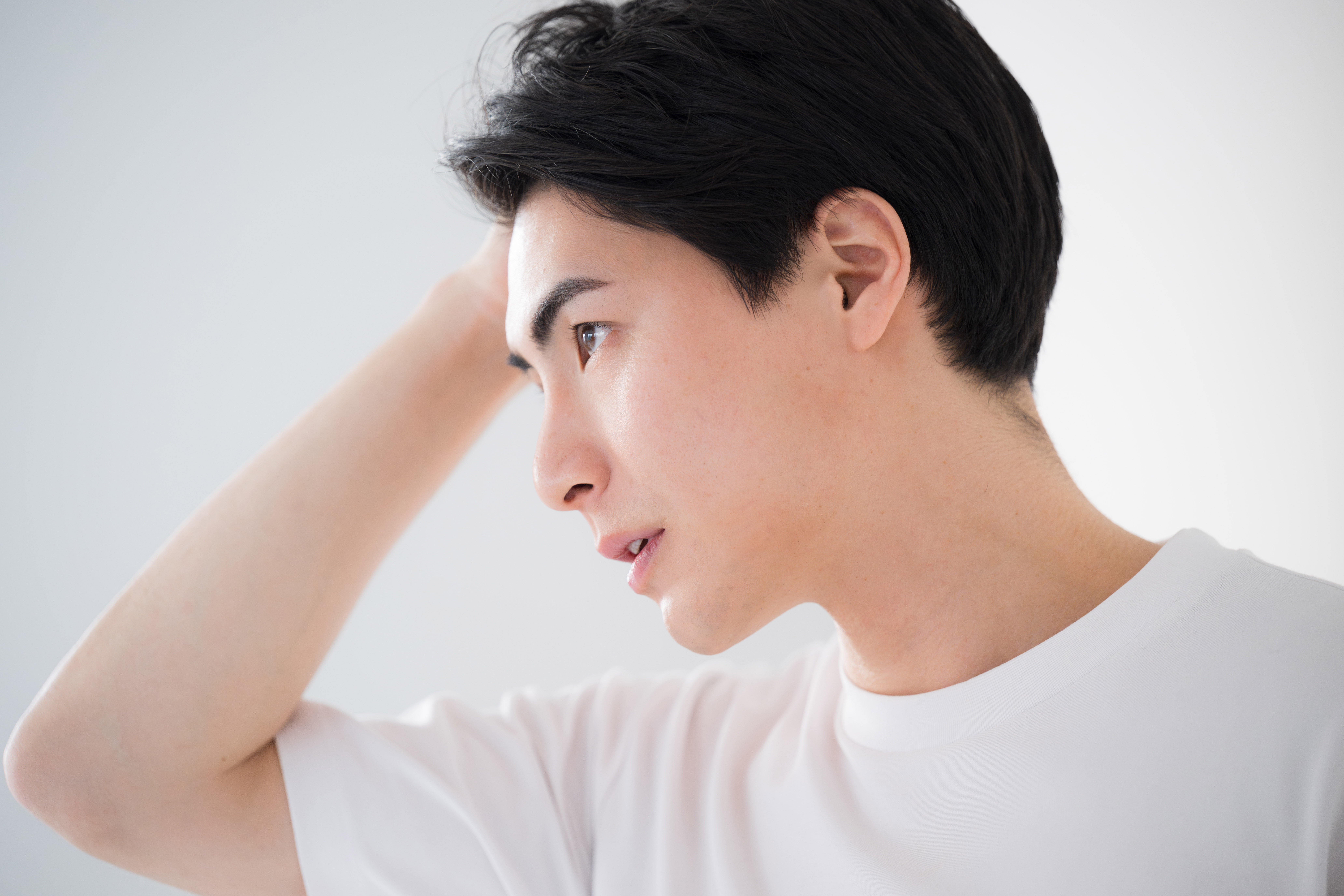髪の生え際を触る男性