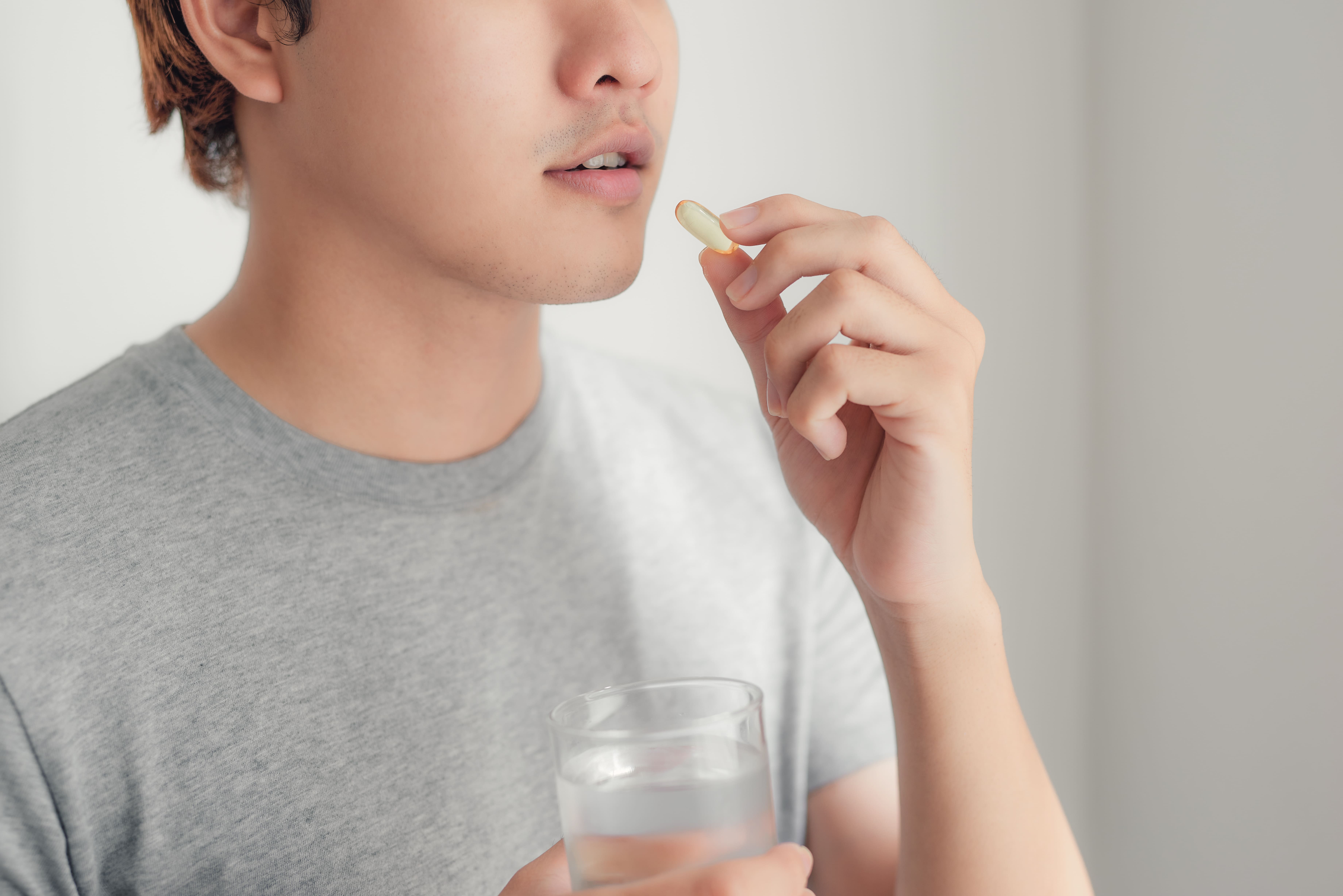 水と一緒に錠剤を飲もうとしている男性