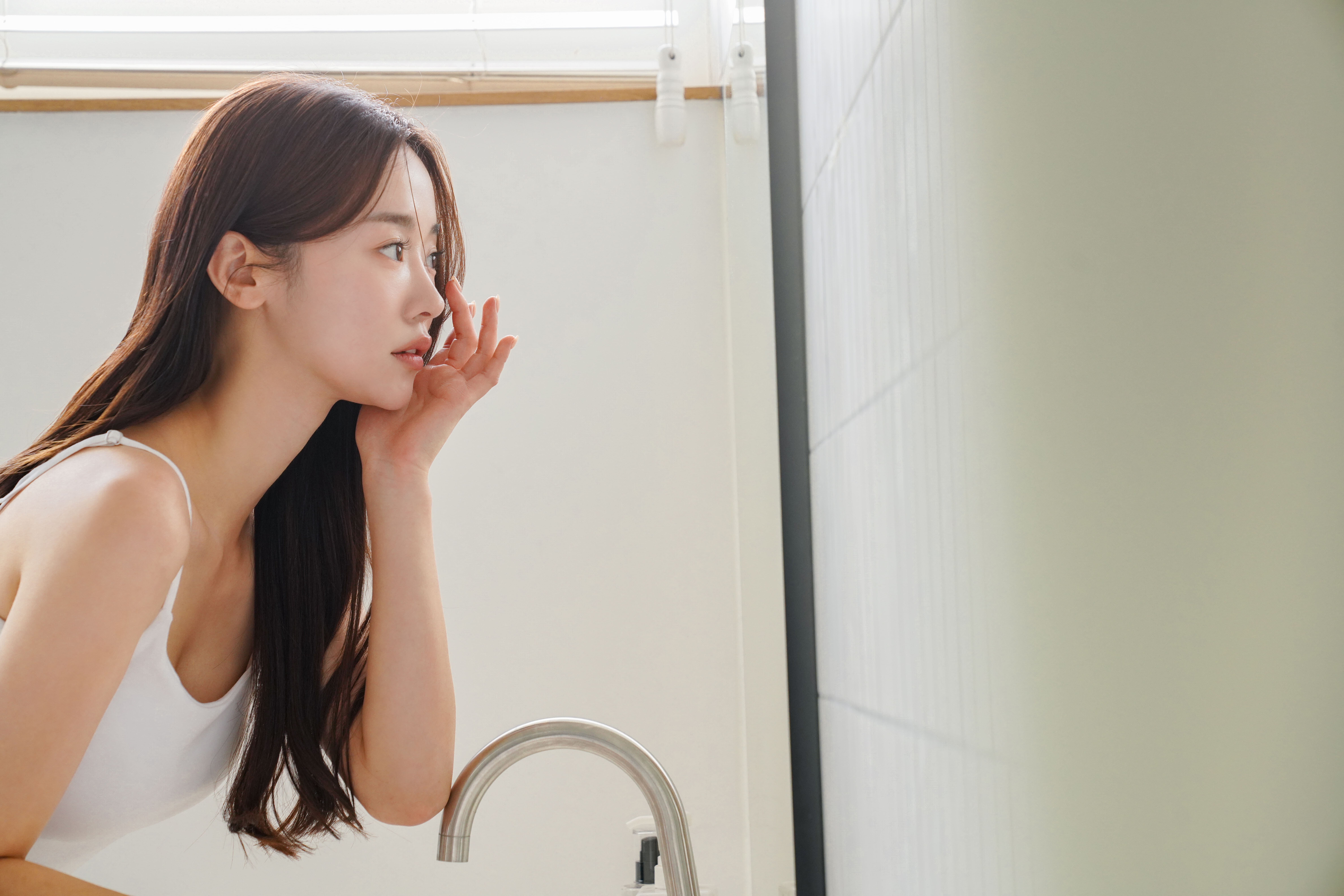 鏡を見ながら眉を気にする女性の様子