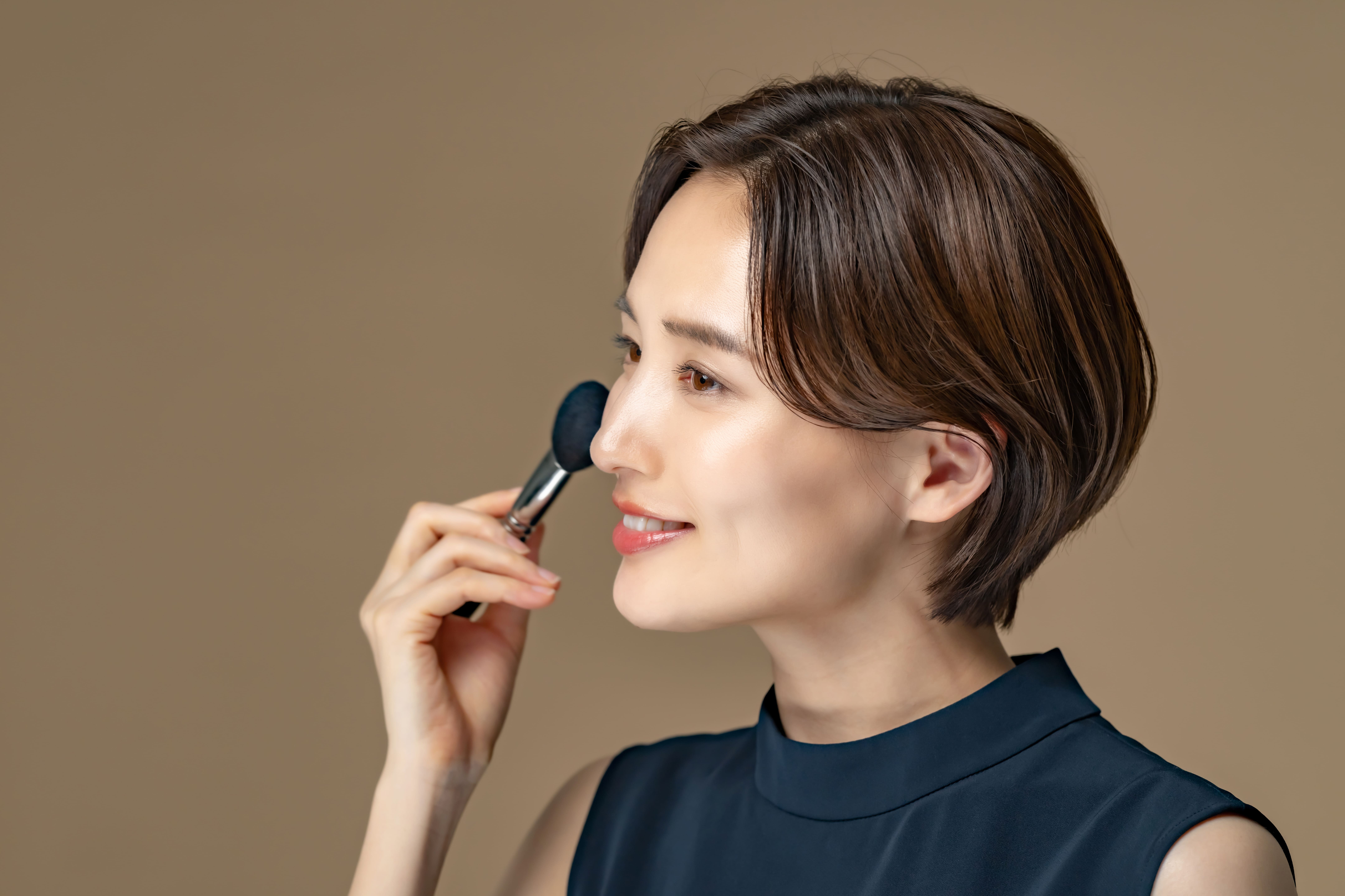 メイクブラシで頬を整える女性