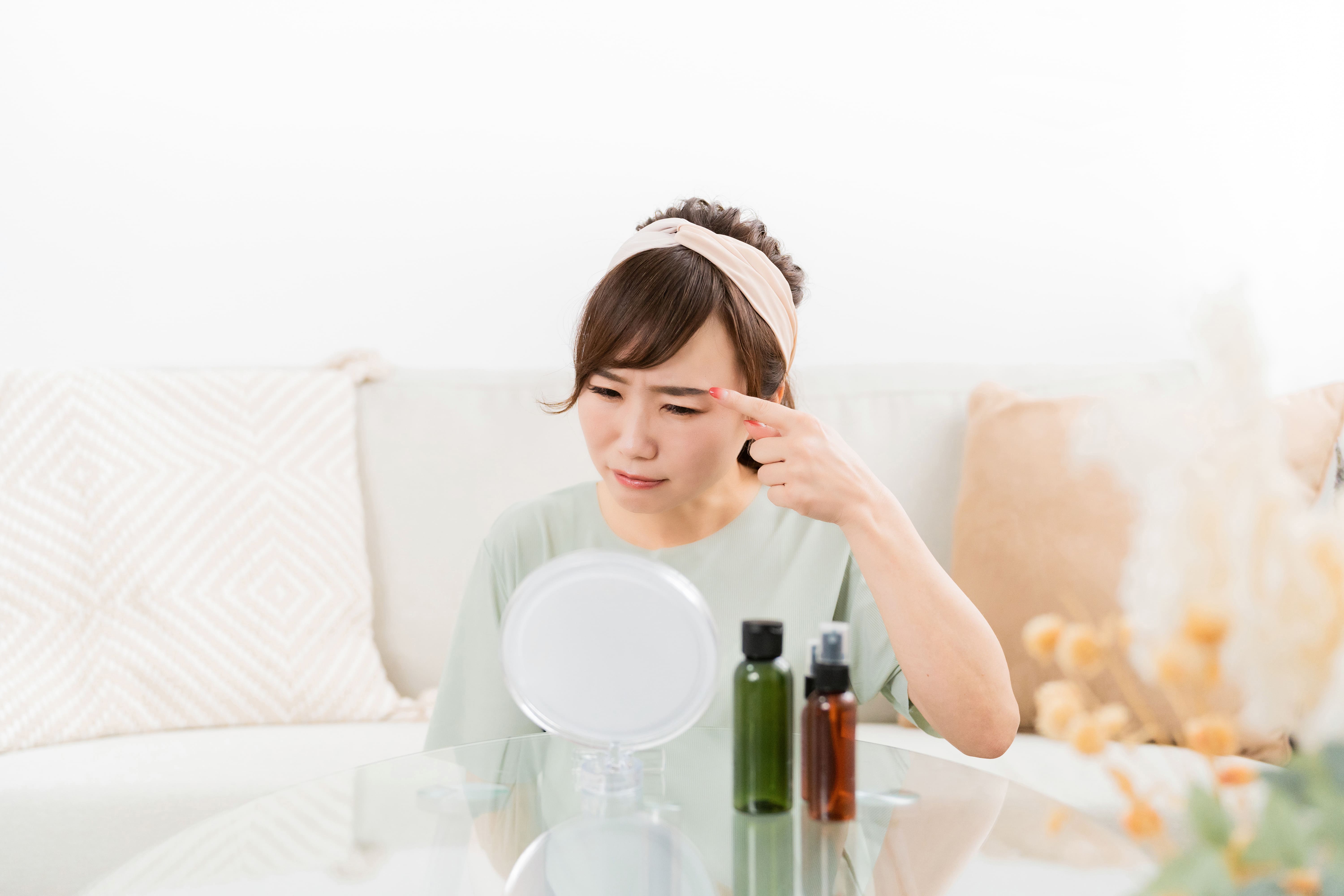 鏡を見ながら眉毛の状態を気にする女性