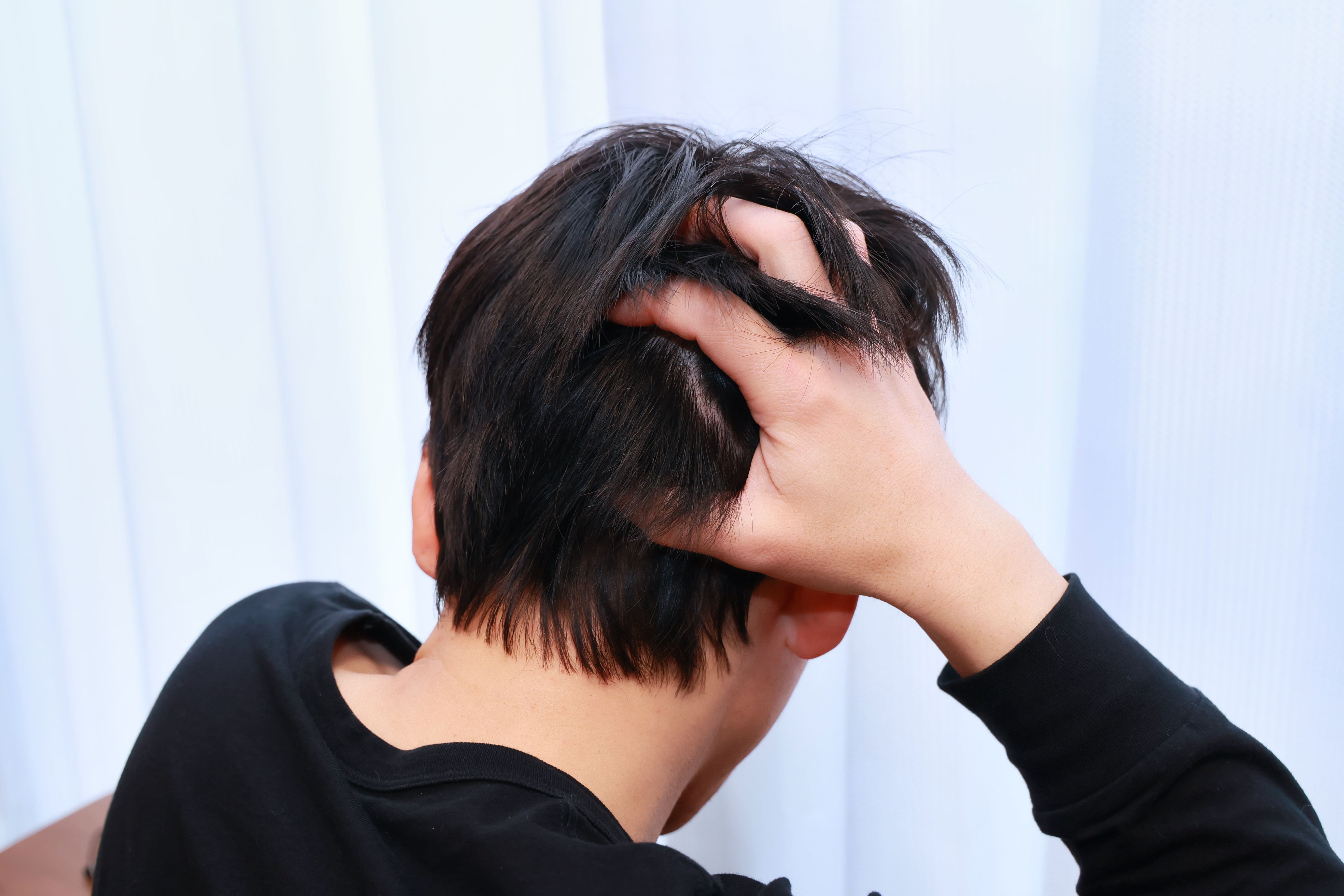 後頭部の薄さが気になり髪をかき上げる男性