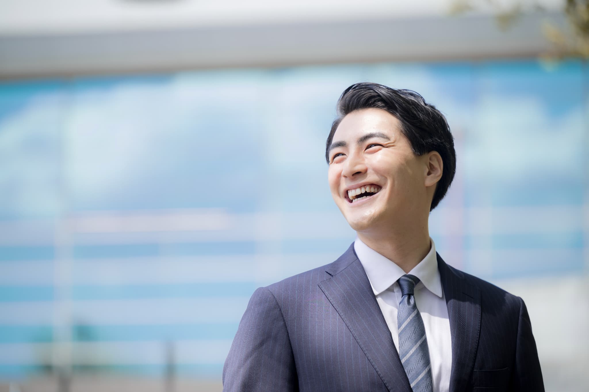 屋外で笑顔を見せるスーツ姿の男性