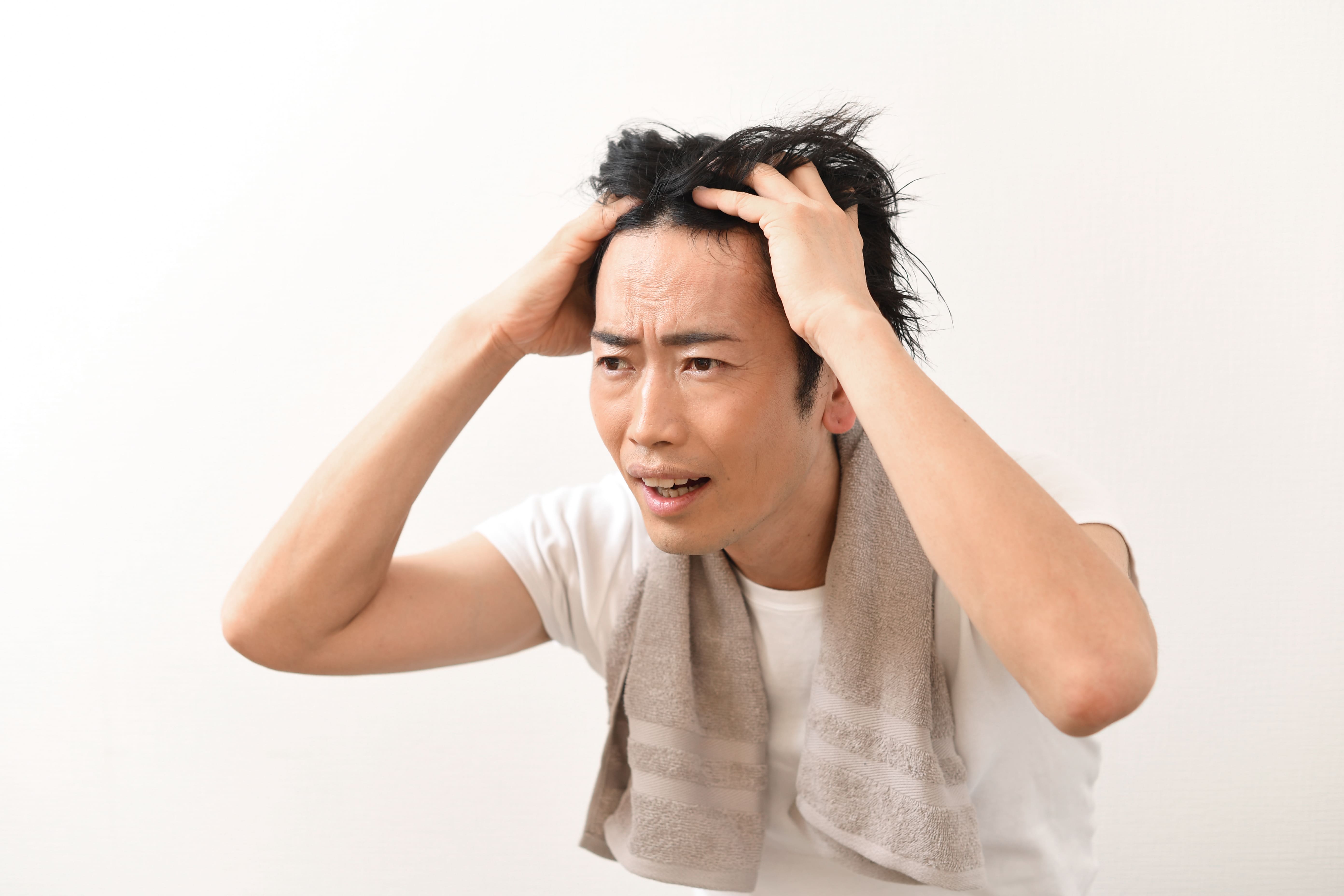 薄毛に悩み、頭をかきむしる男性