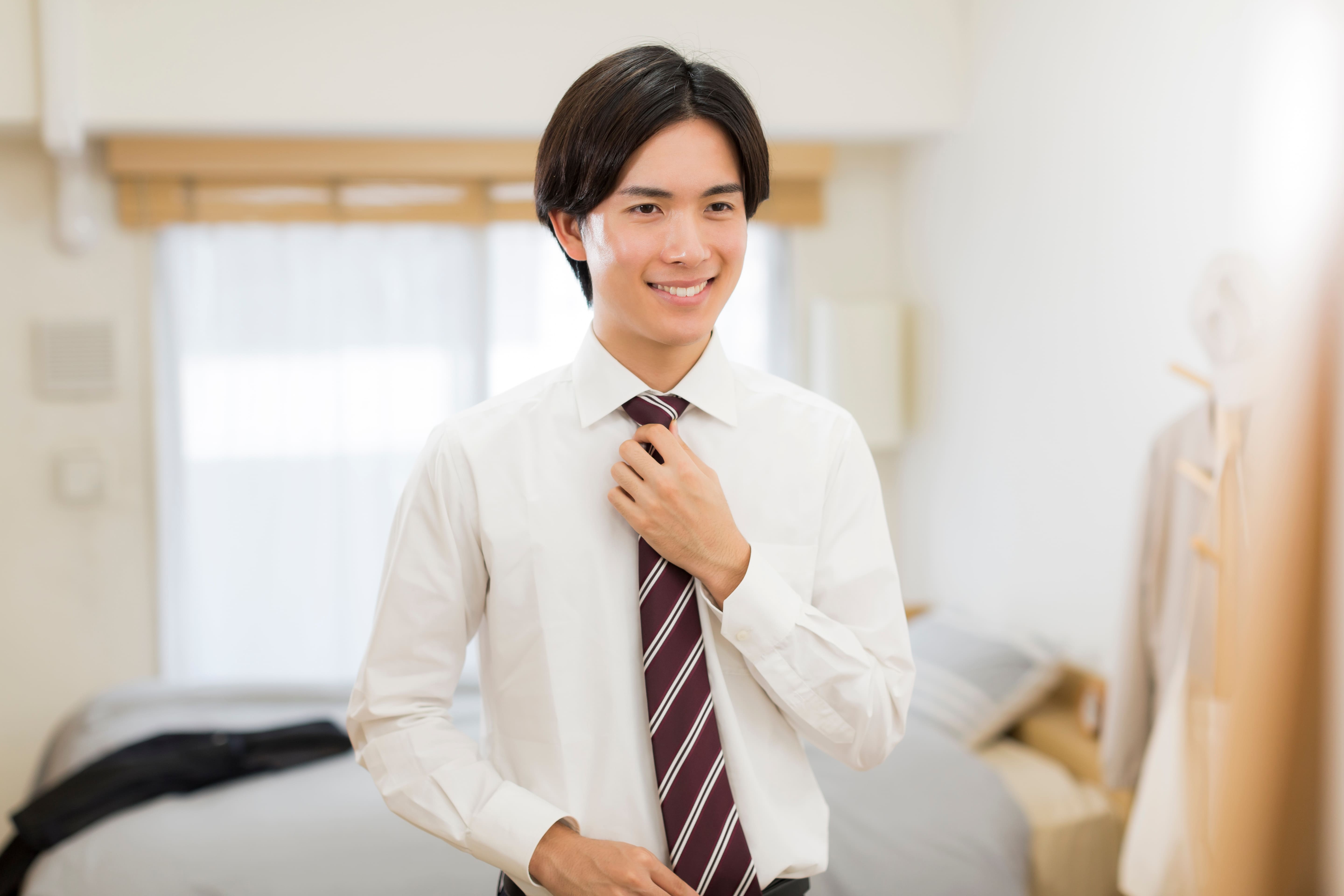 身だしなみを整えながらネクタイを締める男性