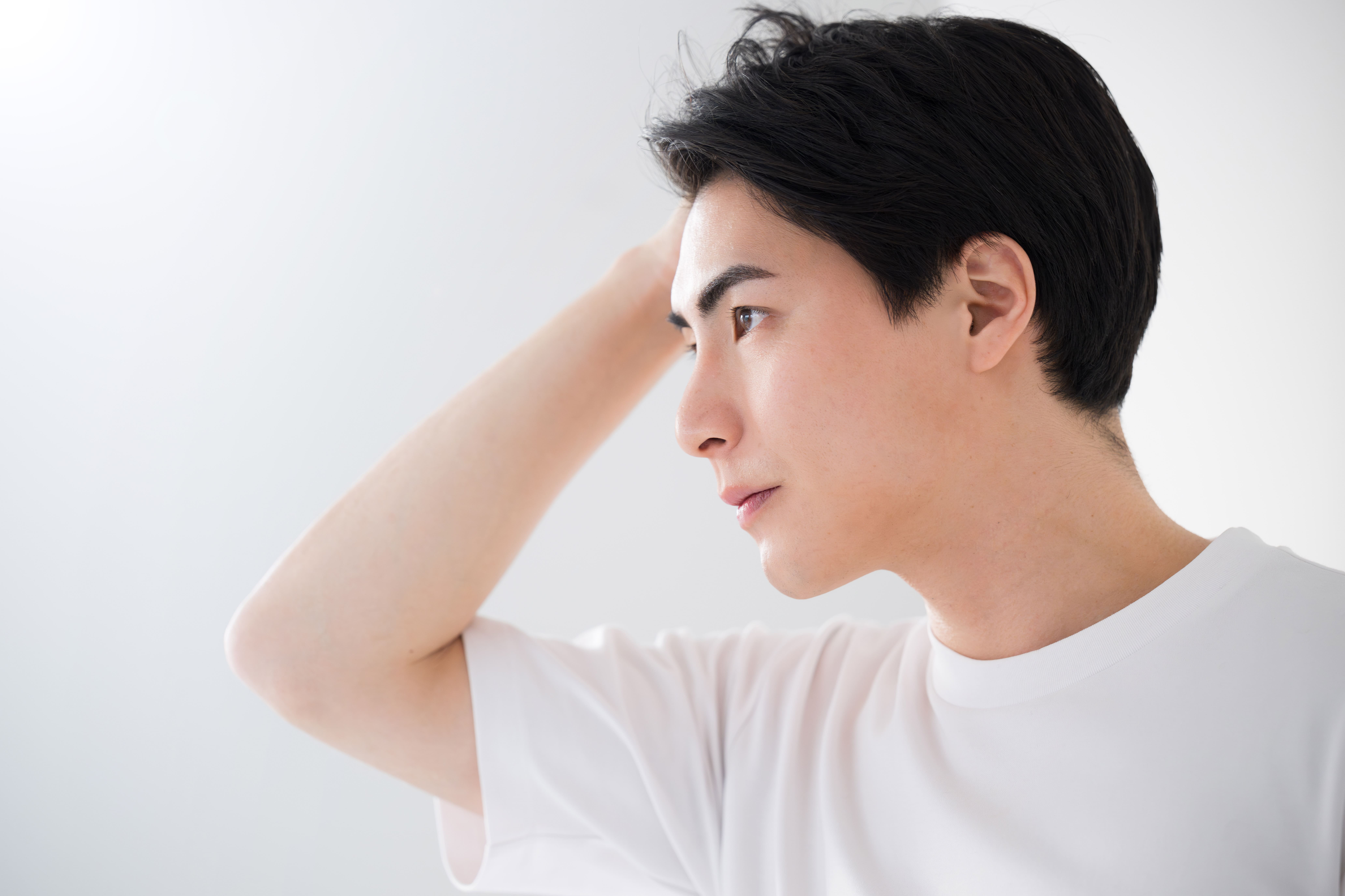 髪の状態を気にして頭に手を当てる男性