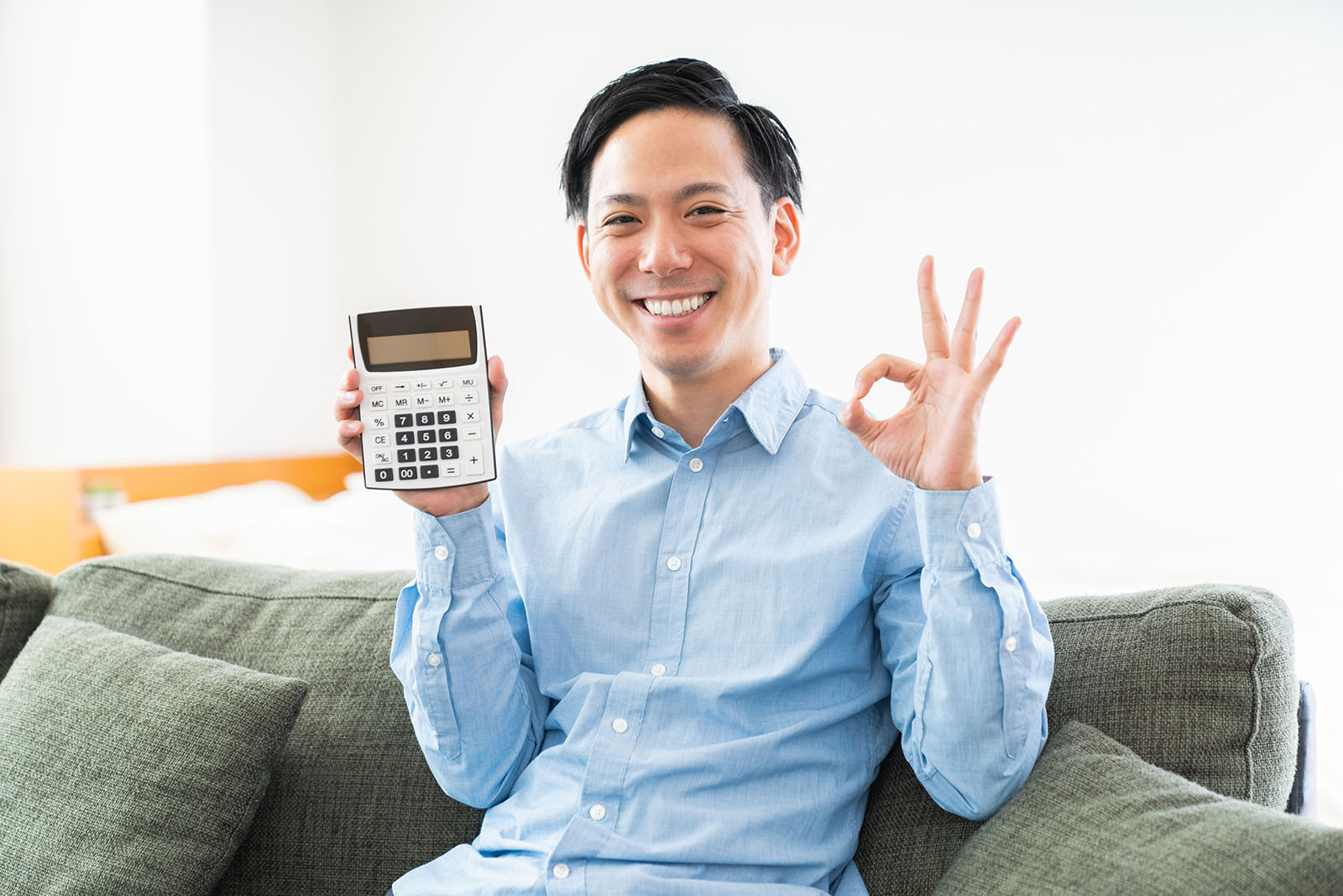 電卓を手に持ち、笑顔でOKサインをする男性